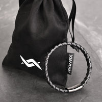 Parker - Single-layer leather bracelet with fishbone pattern next to pouch bag